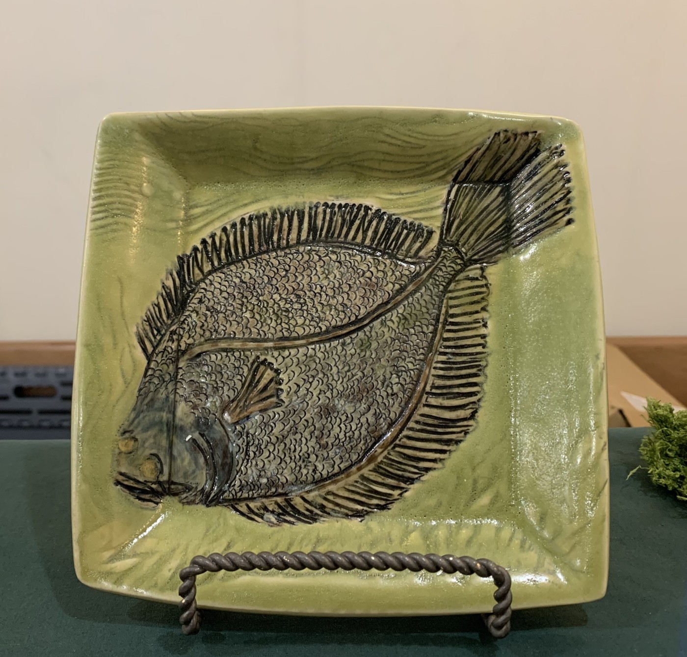 Square plate glazed soft green with a flounder carved in relief across it.