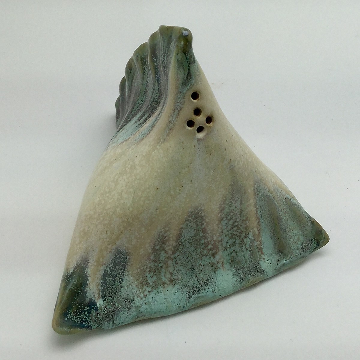 Small pinched salt shaker with a folded triangular form, glazed in cream drifting into sea green and grey