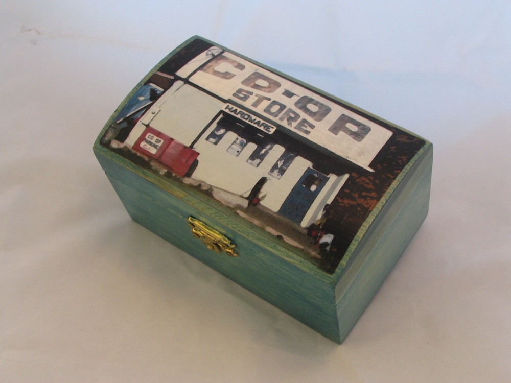 Small hinged box painted teal, the lid showing the Sointula Co-op Store front with its hardware sign